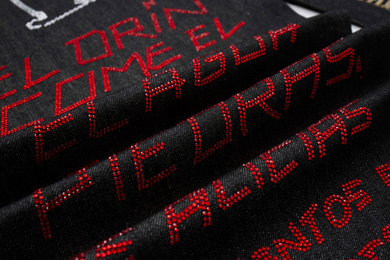 Close-up of black denim fabric with red rhinestone lettering and folded layers