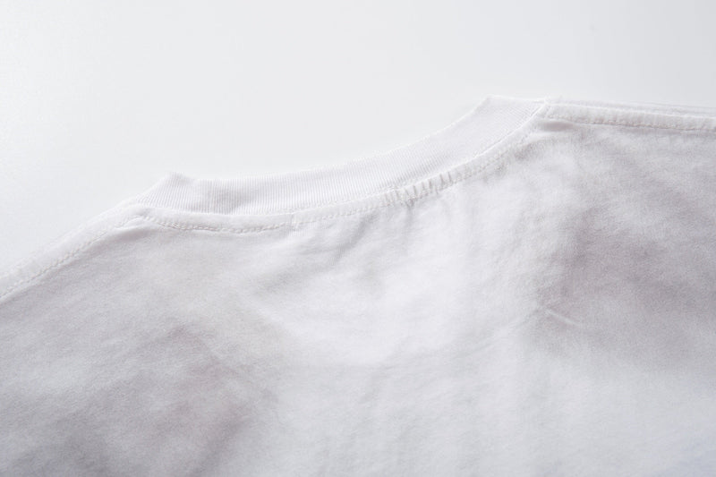 Close-up of a white oversized T-shirt collar and shoulder with distressed washed fabric and visible stitching