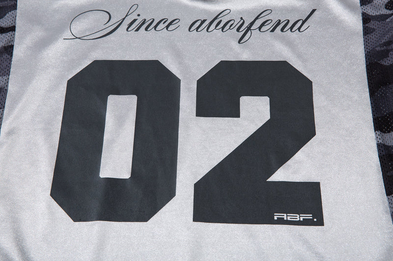 Close-up of front 02 print and side camo mesh panel on light gray jersey top
