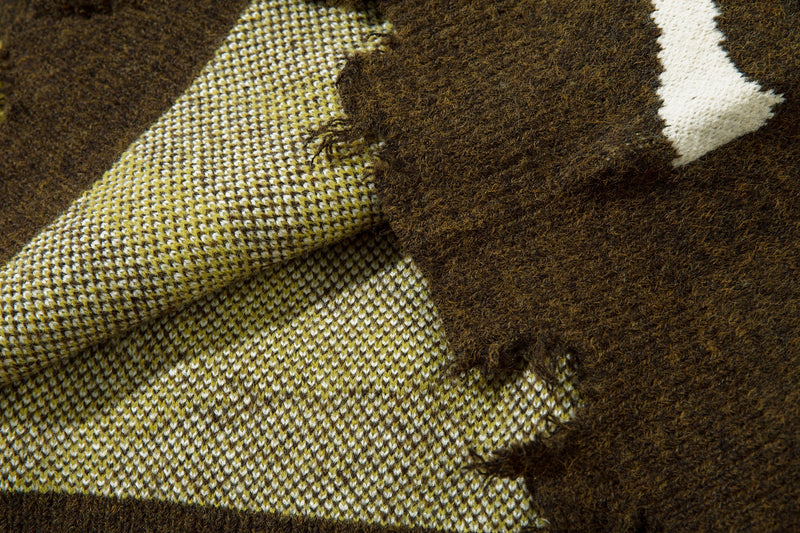 Close-up of sweater knit showing distressed stitch detail and olive, white and yellow camo pattern
