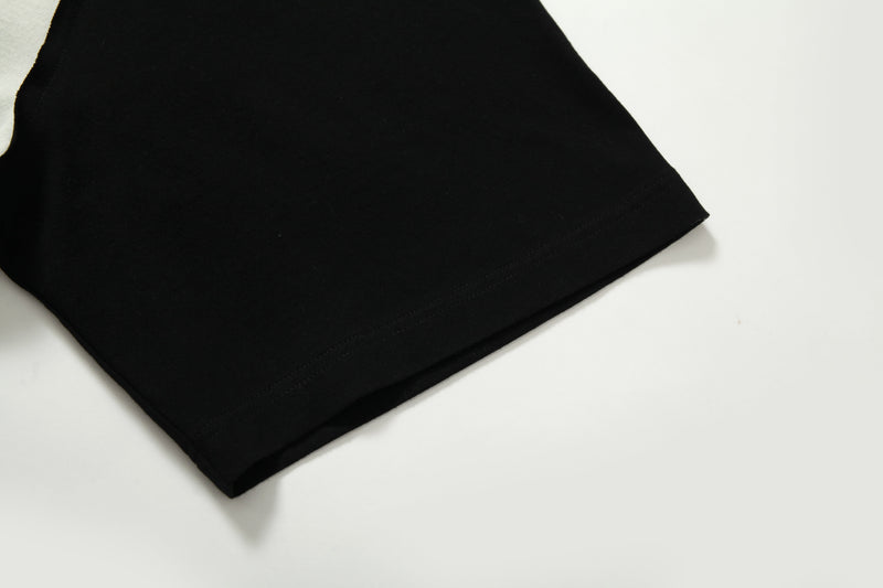 Close-up of a black raglan tee sleeve hem with subtle stitching on a white background