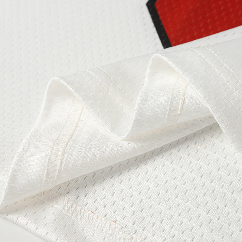 Close-up of white textured football jersey fabric with stitched sleeve and red-black graphic detail on the chest