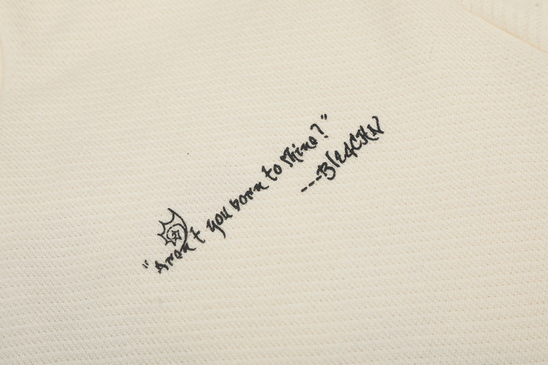 Close-up of small black slogan print on cream sweatshirt fabric