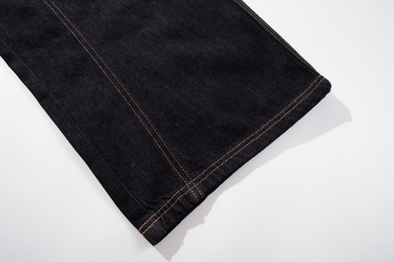 Close-up of dark wash jean hem with tan topstitching
