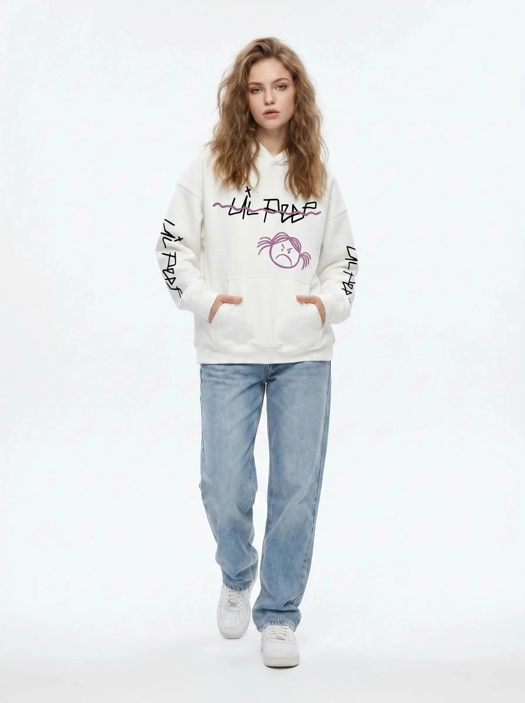 A person with wavy light brown hair wears the Lil Peep Hoodie — Sad Face Graffiti Graphic Sweatshirt, paired with light blue jeans and white sneakers, standing with hands in the hoodie’s pockets against a white background.