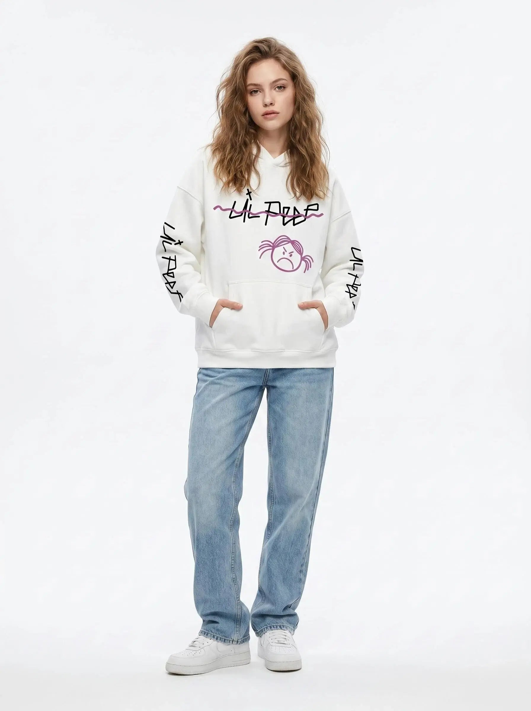 A person with wavy light brown hair wears the Lil Peep Hoodie — Sad Face Graffiti Graphic Sweatshirt, paired with light blue jeans and white sneakers, against a plain white background. Ideal Lil Peep merch for men & women.