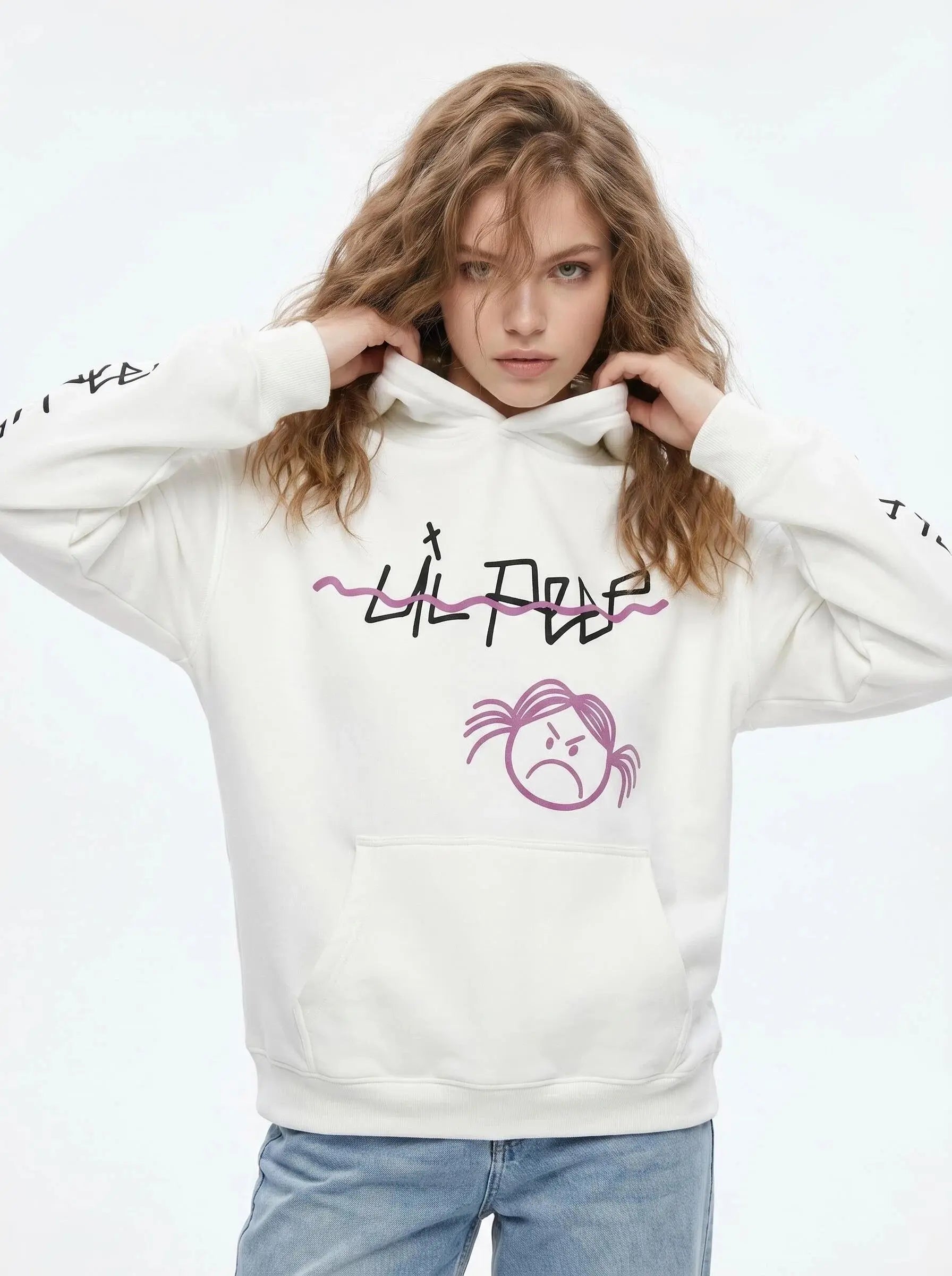 A young woman with wavy blonde hair wears a white Lil Peep Hoodie — Sad Face Graffiti Graphic Sweatshirt, holding the hood with both hands and looking at the camera against a light background.