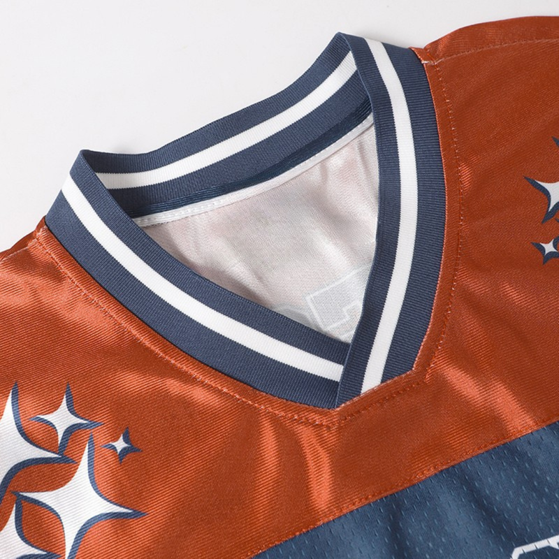 Close-up of a varsity football jersey collar with navy and white stripes on orange mesh fabric with star accents