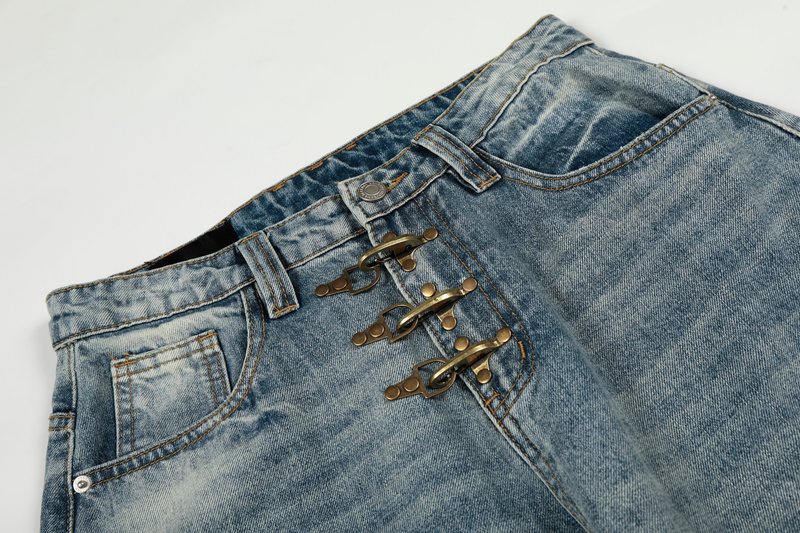Close-up of the front waist on light wash jeans showing metal hook closures and button tab