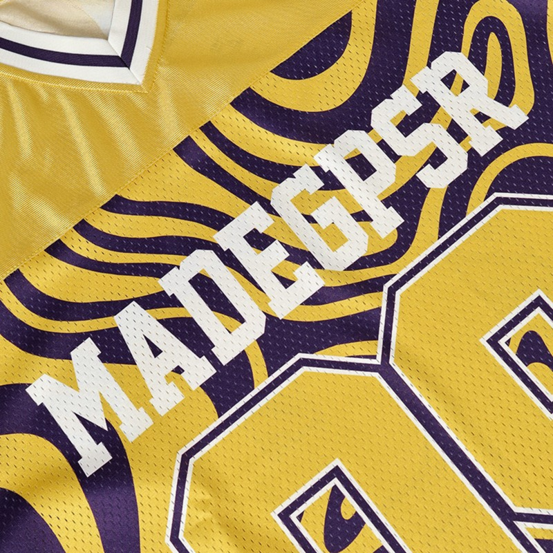 Close-up of a yellow and purple psychedelic football jersey with bold varsity lettering and textured mesh fabric