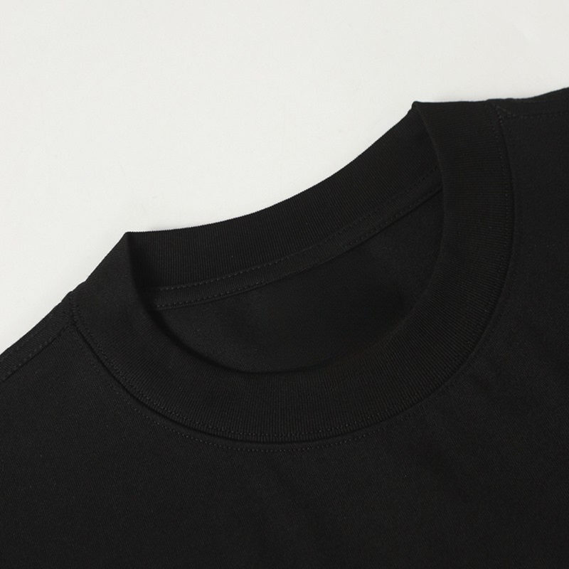 Black cotton T-shirt close-up showing the crew neckline and shoulder seam on a plain white background