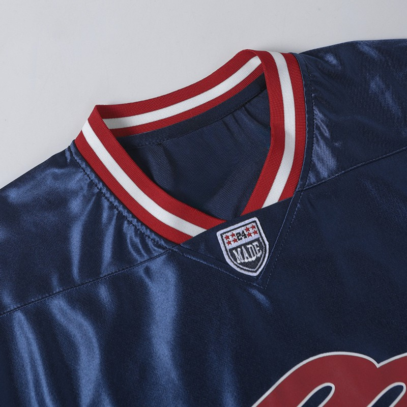 Navy jersey tee with red-and-white ribbed collar and MADE chest logo patch, sporty athletic streetwear style
