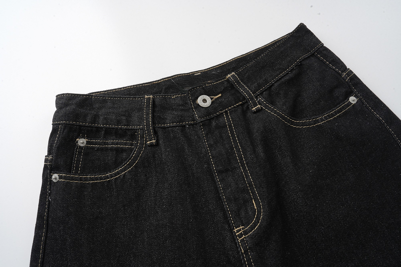 Close-up of black jeans waistband with front pockets, button, and contrast stitching