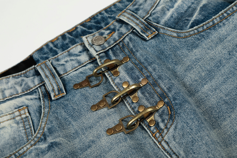Close-up of front waistband on light wash denim pants with three brass hook closures
