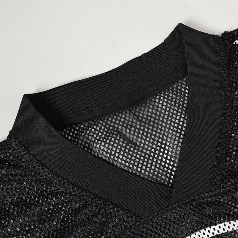 Close-up of a black mesh football jersey with ribbed trim and gothic streetwear texture on a white background