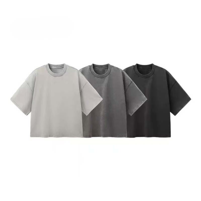 Three oversized washed cotton T-shirts in light gray, charcoal, and black on a white background