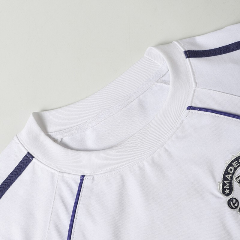 White football jersey T-shirt with navy piping, ribbed collar, and embroidered chest crest for streetwear style
