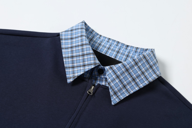 Close-up of blue plaid collar and half-zip neckline on navy pullover