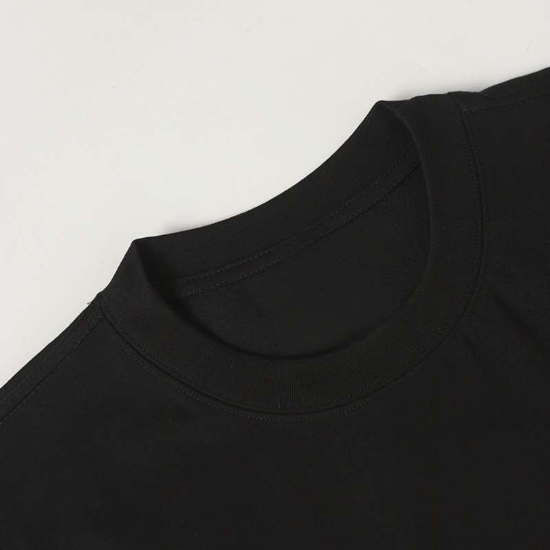 Black cotton crew neck tee with a close-up of the collar and seam detailing on a plain white background
