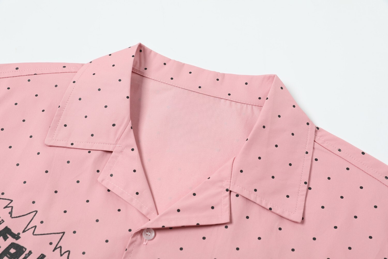 Close-up of pink shirt collar and shoulder with black polka dots
