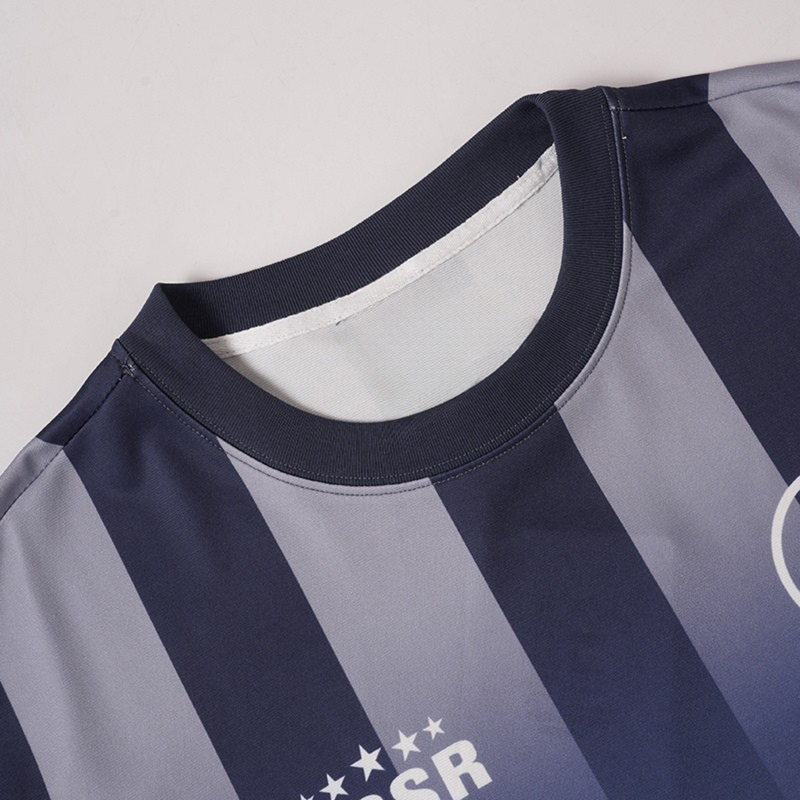 Close-up of a navy and light gray striped performance soccer jersey with a ribbed crew neck and printed chest logo