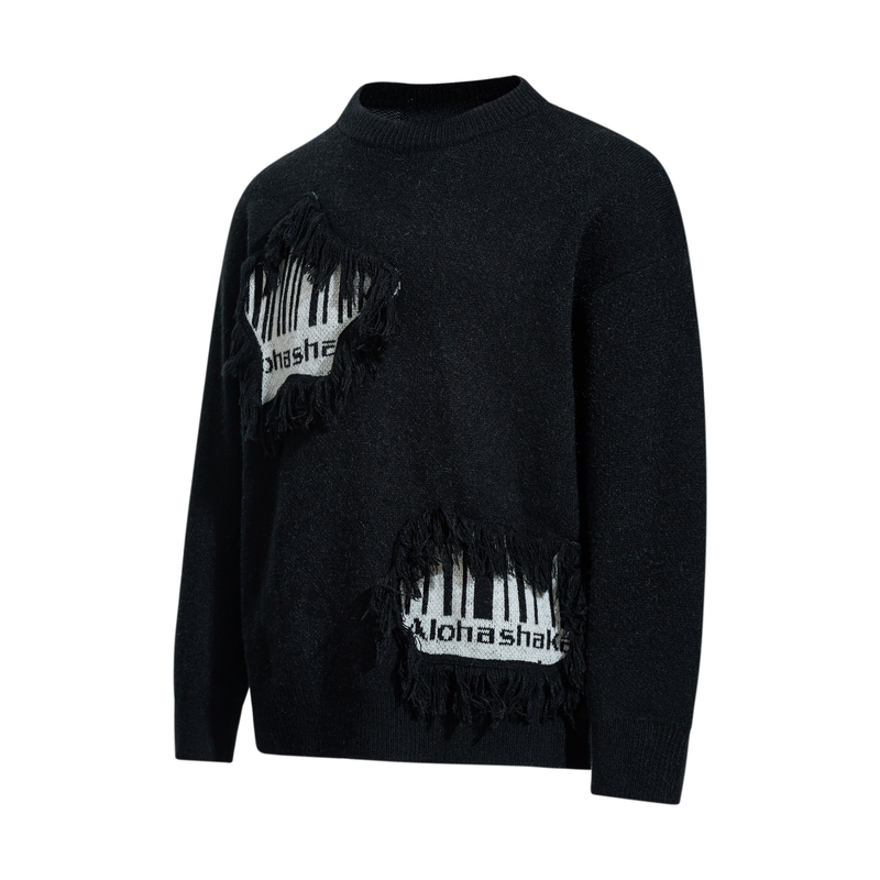 Black knit sweater angled front view with fringe patch on chest and lower hem