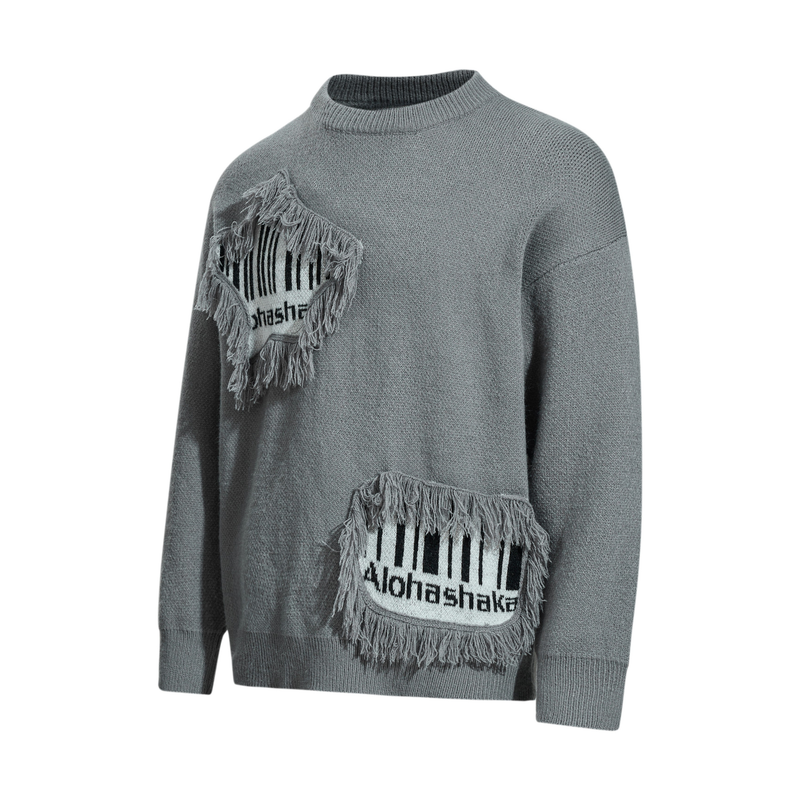 Gray knit sweater angled front view with fringe patch on chest and lower hem
