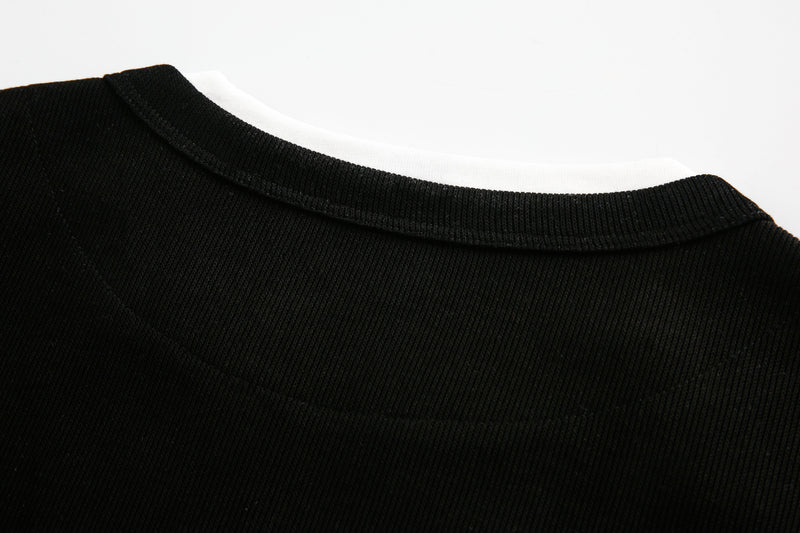 Close-up of black ribbed neckline with white collar trim