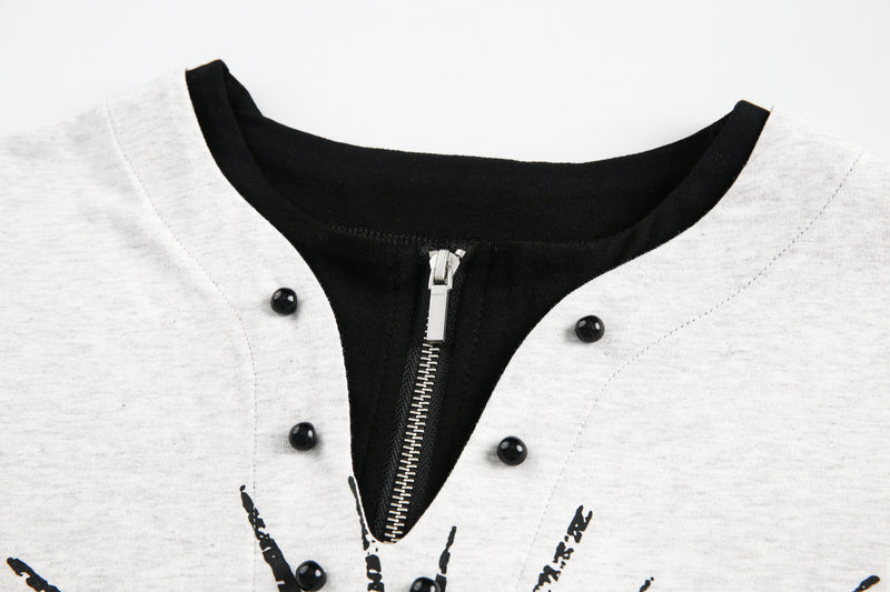 Close-up of black zipper placket and snap buttons on light gray long-sleeve tee