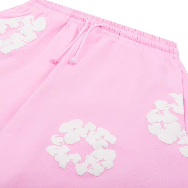 The Pink “Cotton Wreath” Denim Tears Sweatpants feature white floral prints on light pink streetwear pants, complete with an elastic waistband and drawstring—showcasing Denim Tears’ iconic cotton wreath-inspired style.