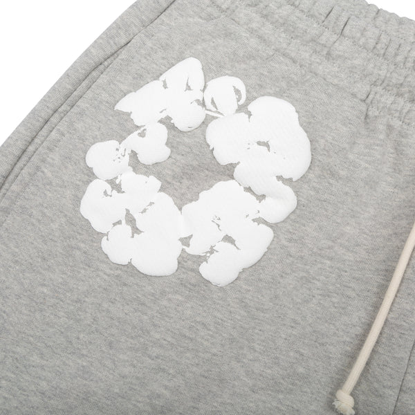 Close-up of Grey “Cotton Wreath” Denim Tears Sweatpants—streetwear pants with an elastic waistband, white drawstring, and a circular white floral print graphic inspired by the classic Denim Tears design.