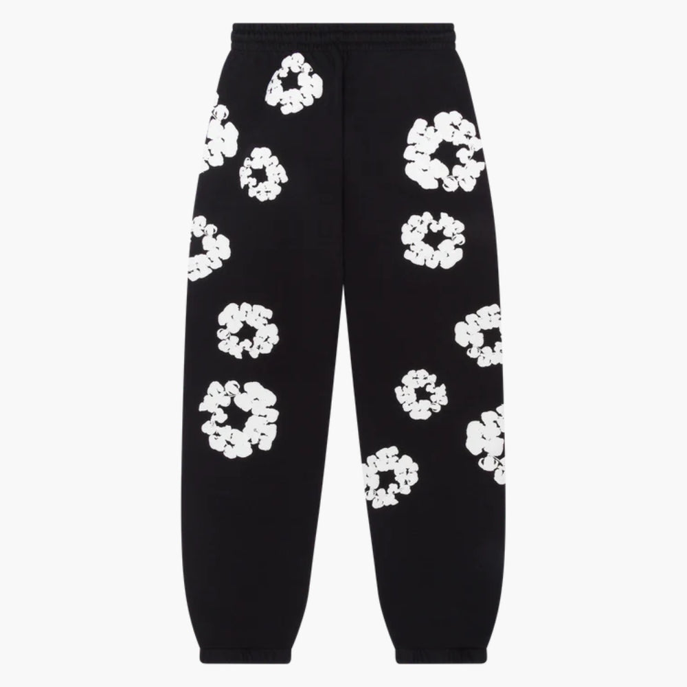 The Black "Cotton Wreath" Denim Tears Sweatpants are streetwear pants with a relaxed fit, showcasing bold white floral prints scattered across the black fabric for a striking look.