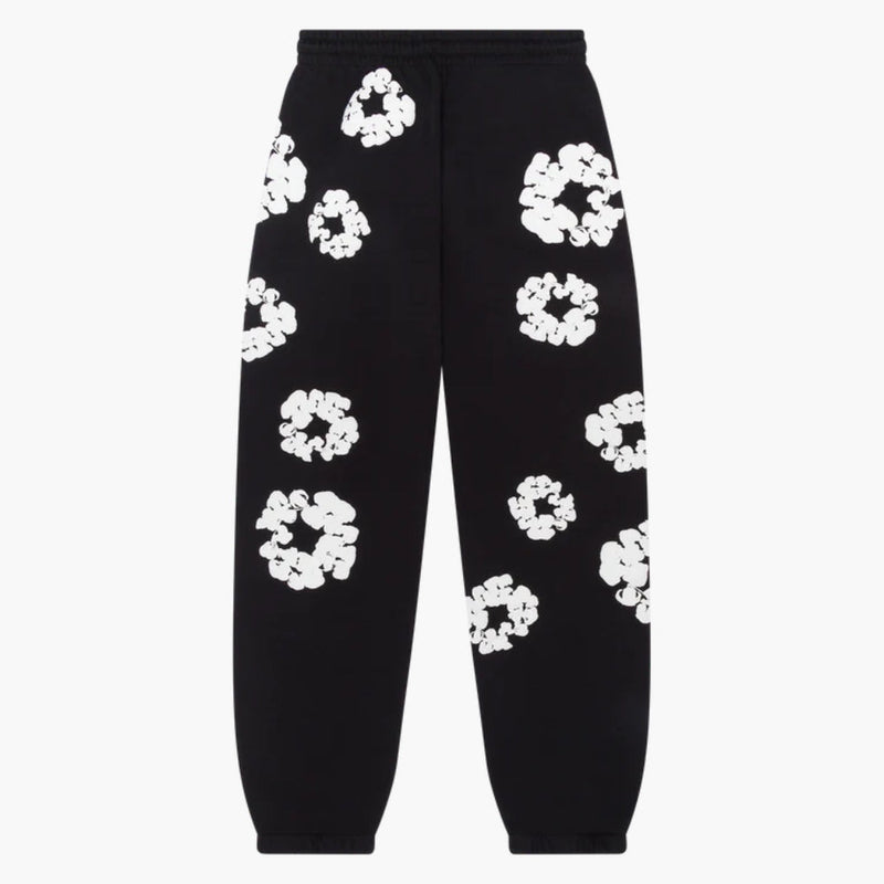 The Black "Cotton Wreath" Denim Tears Sweatpants are streetwear pants with a relaxed fit, showcasing bold white floral prints scattered across the black fabric for a striking look.