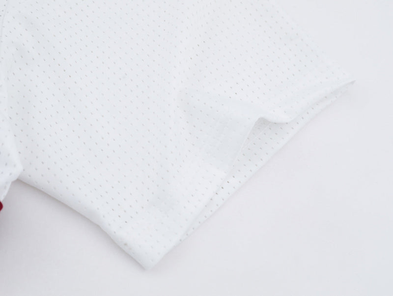 White mesh jersey fabric with tiny perforations, showing a lightweight baseball stitch tee texture on a clean background