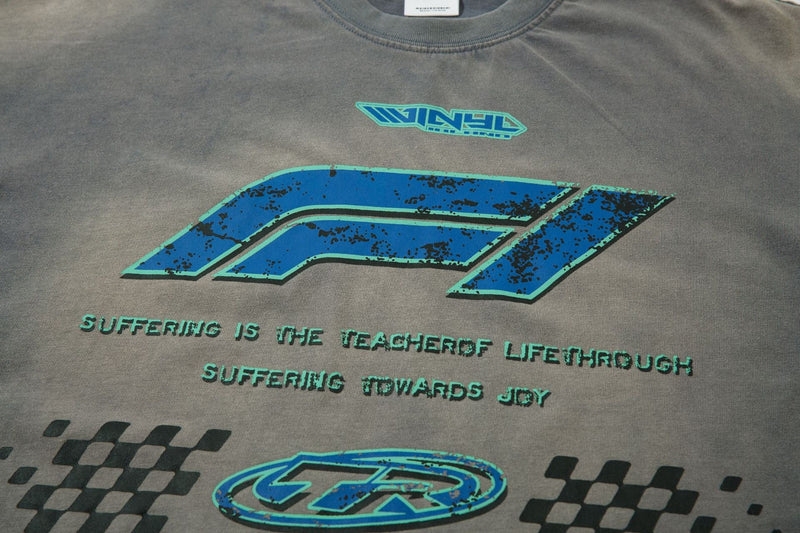 Close-up of gray tee front with blue TR logo, slogan text, and checkered accents