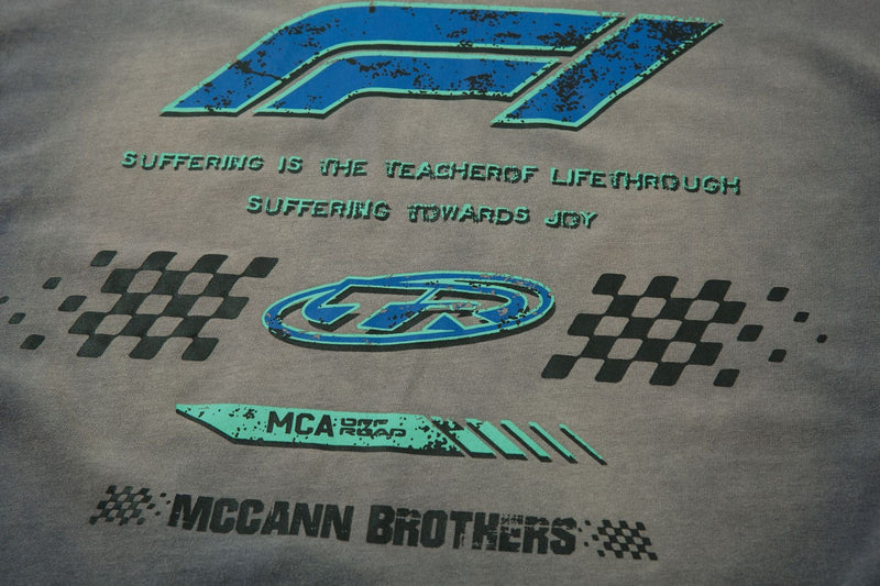 Close-up of gray tee front with blue TR logo, racing bar, and McCann Brothers text