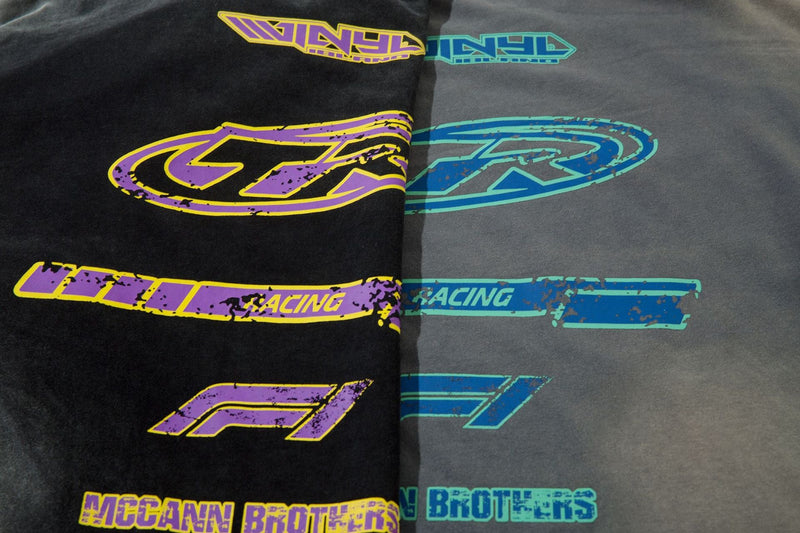 Close-up of black and gray tee fronts showing purple and blue racing graphics side by side
