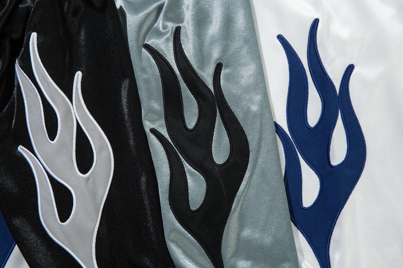 Close-up of flame graphics in white, black, and blue on three jersey colorways