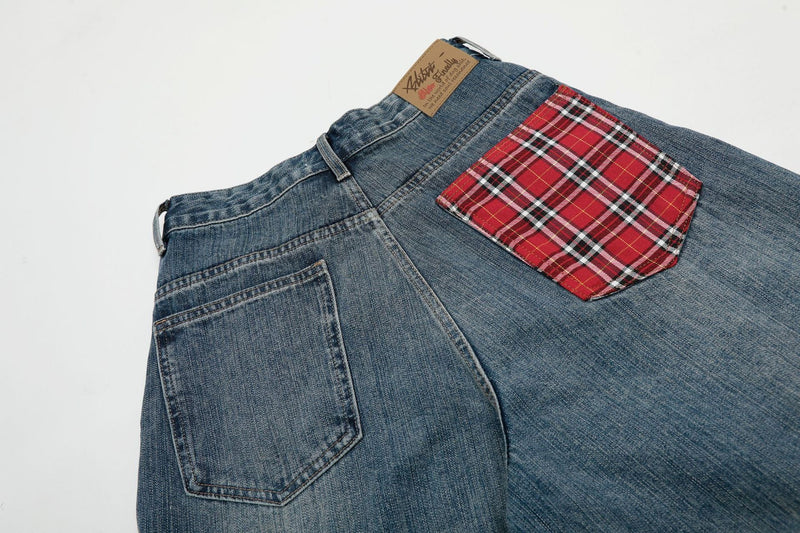 Angled close-up of back waistband and plaid pocket on blue denim shorts
