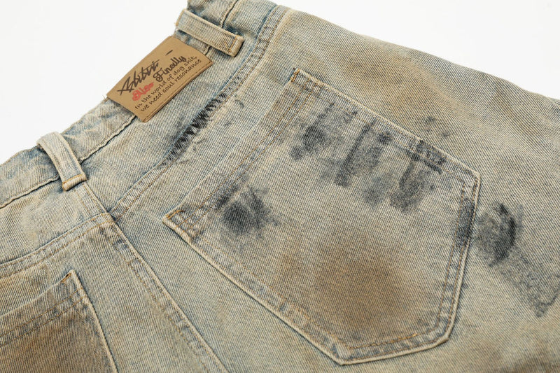 Close-up of back pocket on spray-dyed denim shorts with tan brand label
