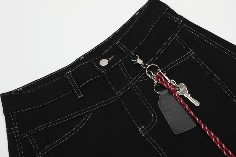 Close-up of black shorts waistband with snap button, belt loops and hanging keychain