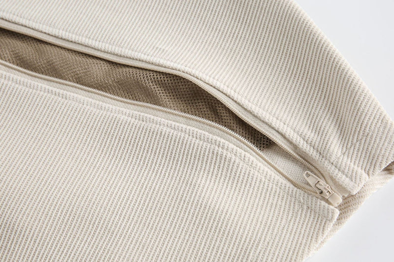 Close-up of a beige ribbed layered chest panel tee with exposed zipper detail and structured minimalist texture
