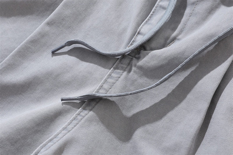 Close-up of light gray drawstring cords and front seam on casual shorts