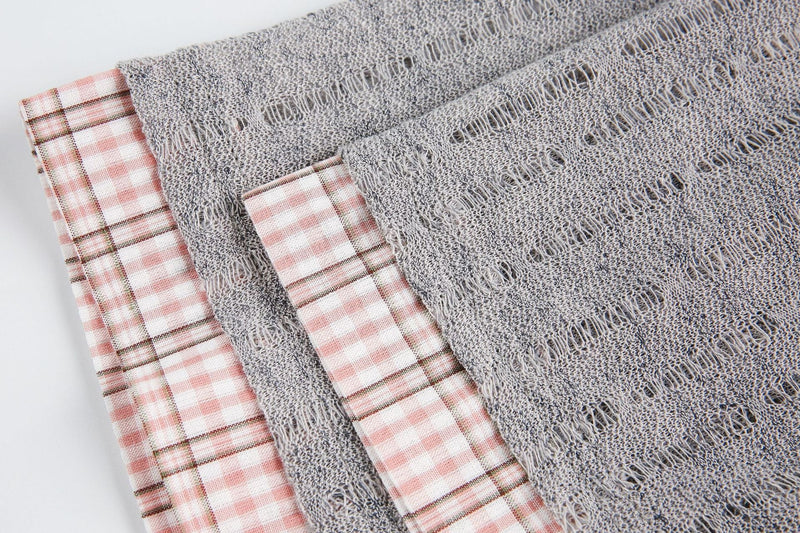 Close-up of a gray mesh graphic tee with frayed texture and pink plaid collar detail on white background