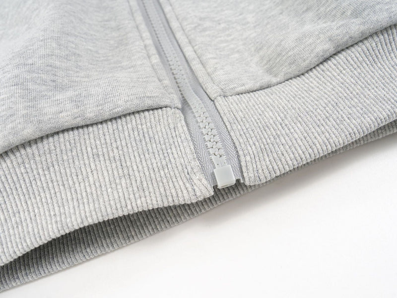 Close-up of the light gray hoodie ribbed hem and zipper bottom