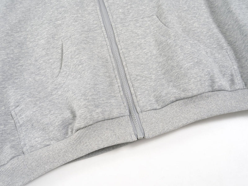 Close-up of the light gray hoodie front pocket area and ribbed hem