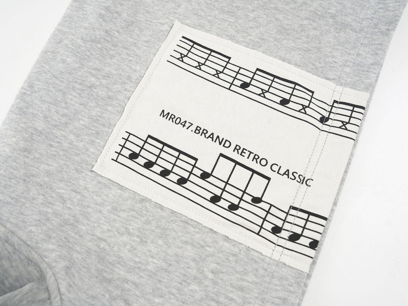 Close-up of the printed music-note patch on the light gray hoodie sleeve