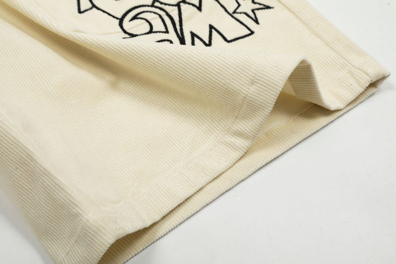 Close-up of cream corduroy shorts hem with star graphic partially visible