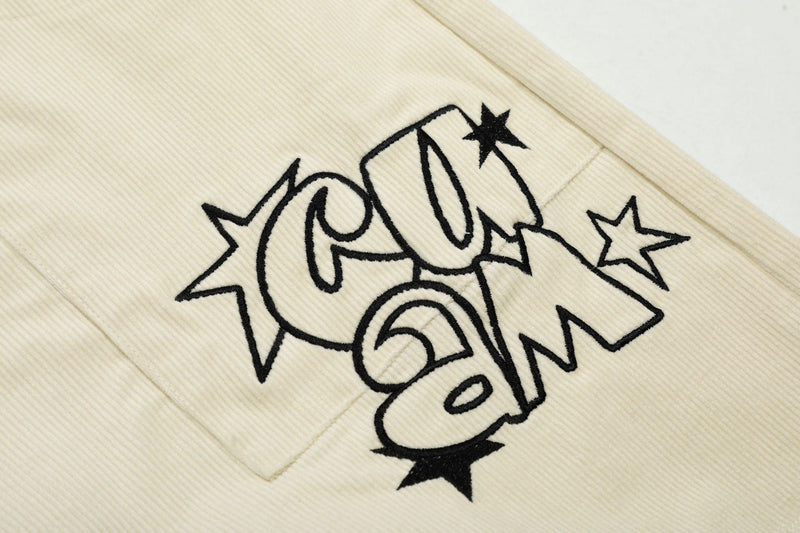 Close-up of black star graphic on cream corduroy shorts