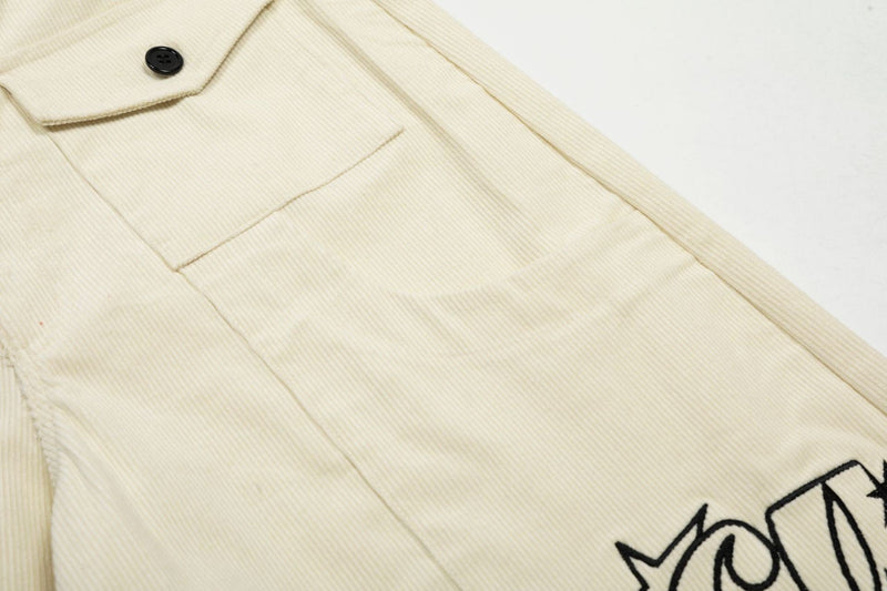 Close-up of cream corduroy shorts front panel and pocket flap with black button